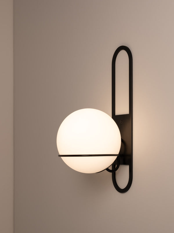 Cradle wall sconce shown in blackened steel finish, side angle, illuminated