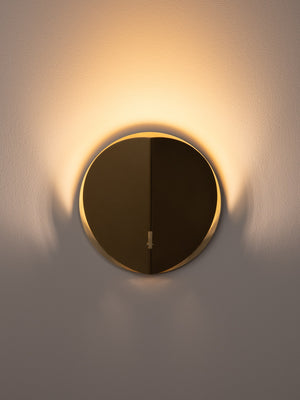 Folded wall sconce shown in natural brass finish, front view, illuminated