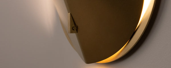 Folded wall sconce shown in natural brass finish, zoomed in to detail of structural pin