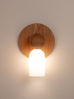 Libby wall sconce shown in warm oak finish, front view, illuminated